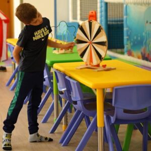 Copilul se joaca atent cu o jucarie sub forma de roata a norocului